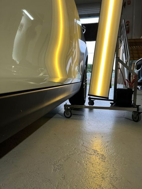 A White Car Is Sitting on A Cart In A Garage — Dent Motive in Runaway Bay, QLD