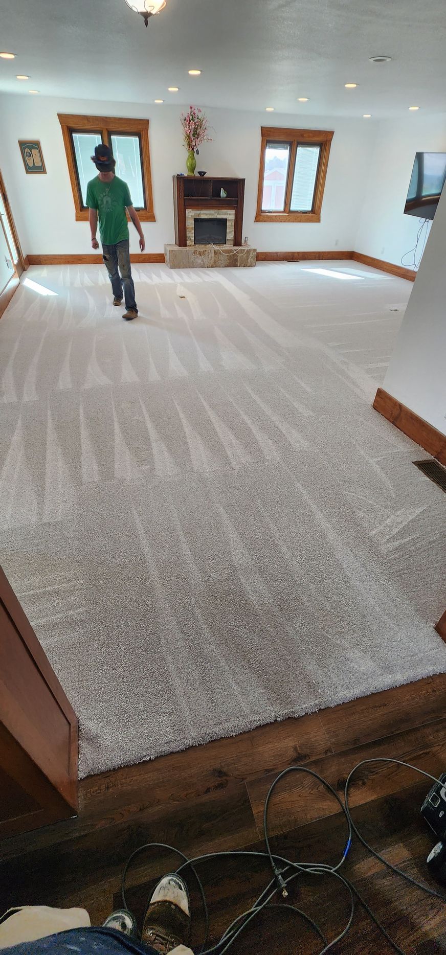 Person walking in a room with light grey carpet, fireplace, and windows.