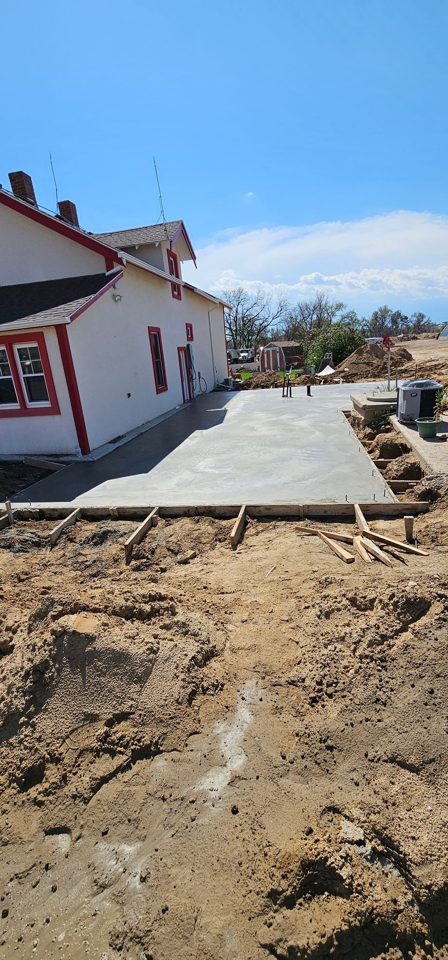 A man is digging in a pile of concrete with a shovel.