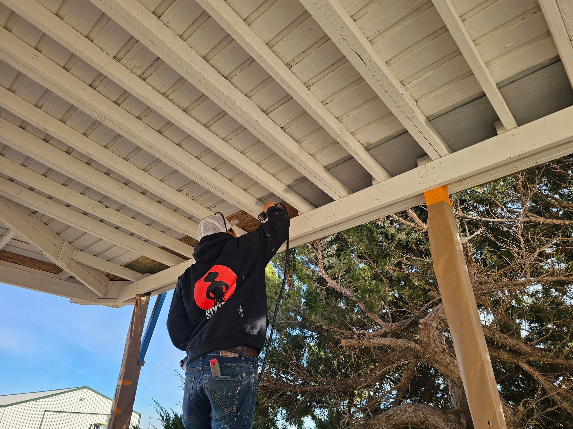 A man is standing on a ladder under a white roof.