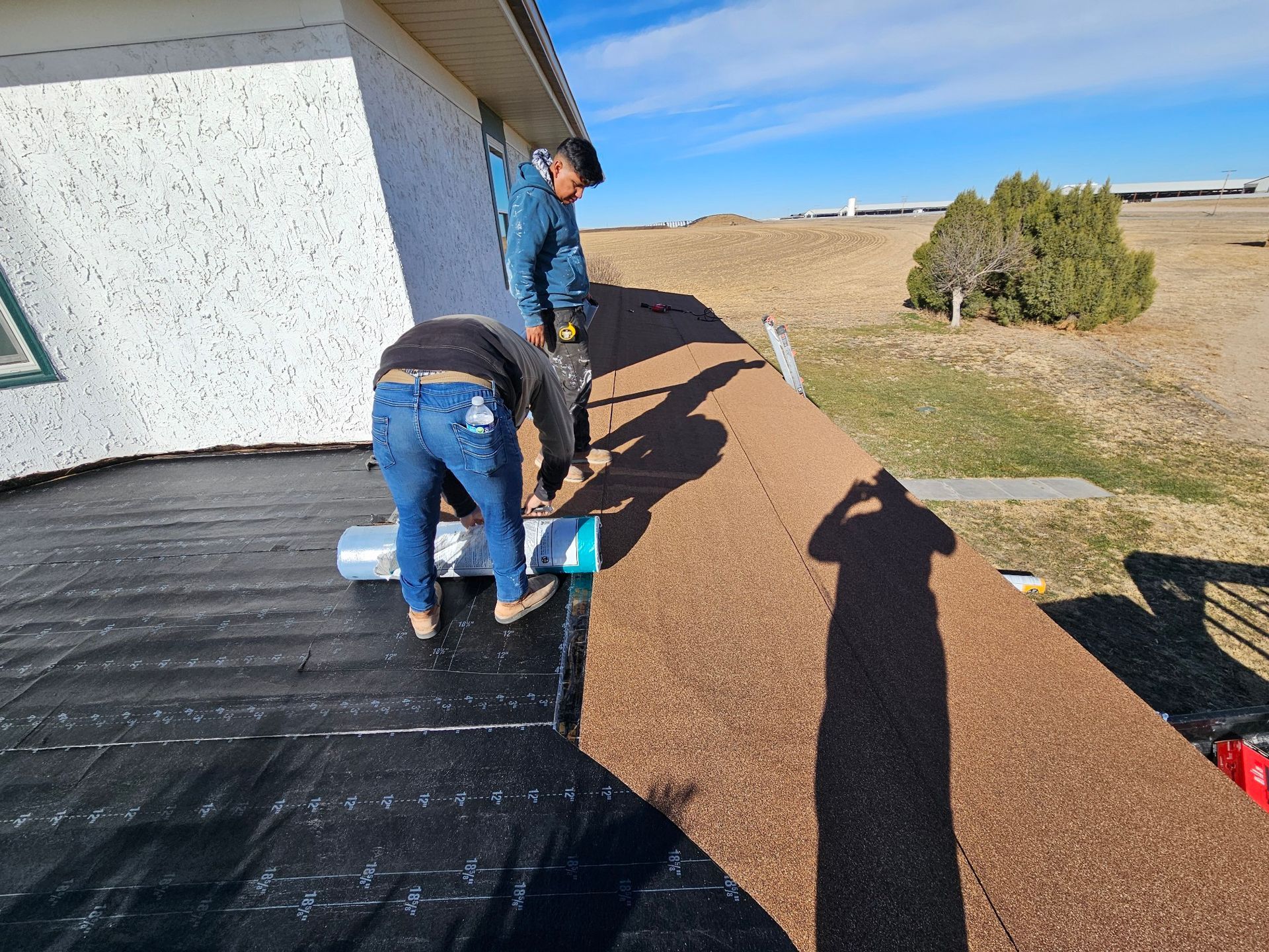 Two men are working on a roof of a house.
