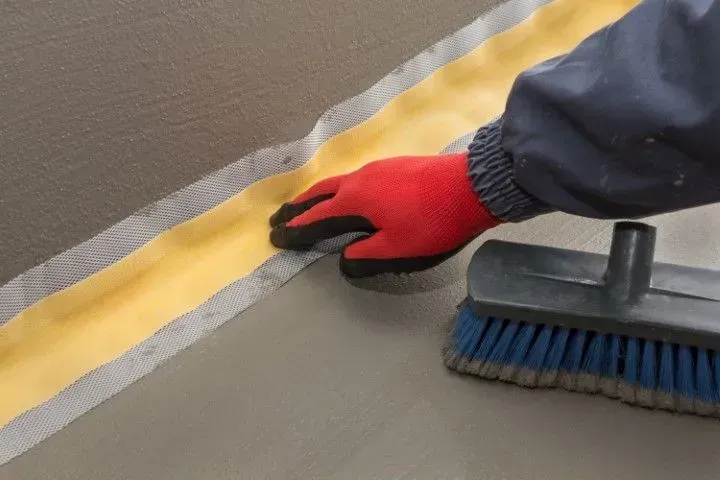 Applying waterproof membrane and sealant to basement floor.