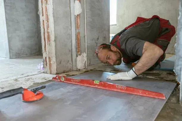 Worker using a spirit level for concrete floor leveling and lifting.