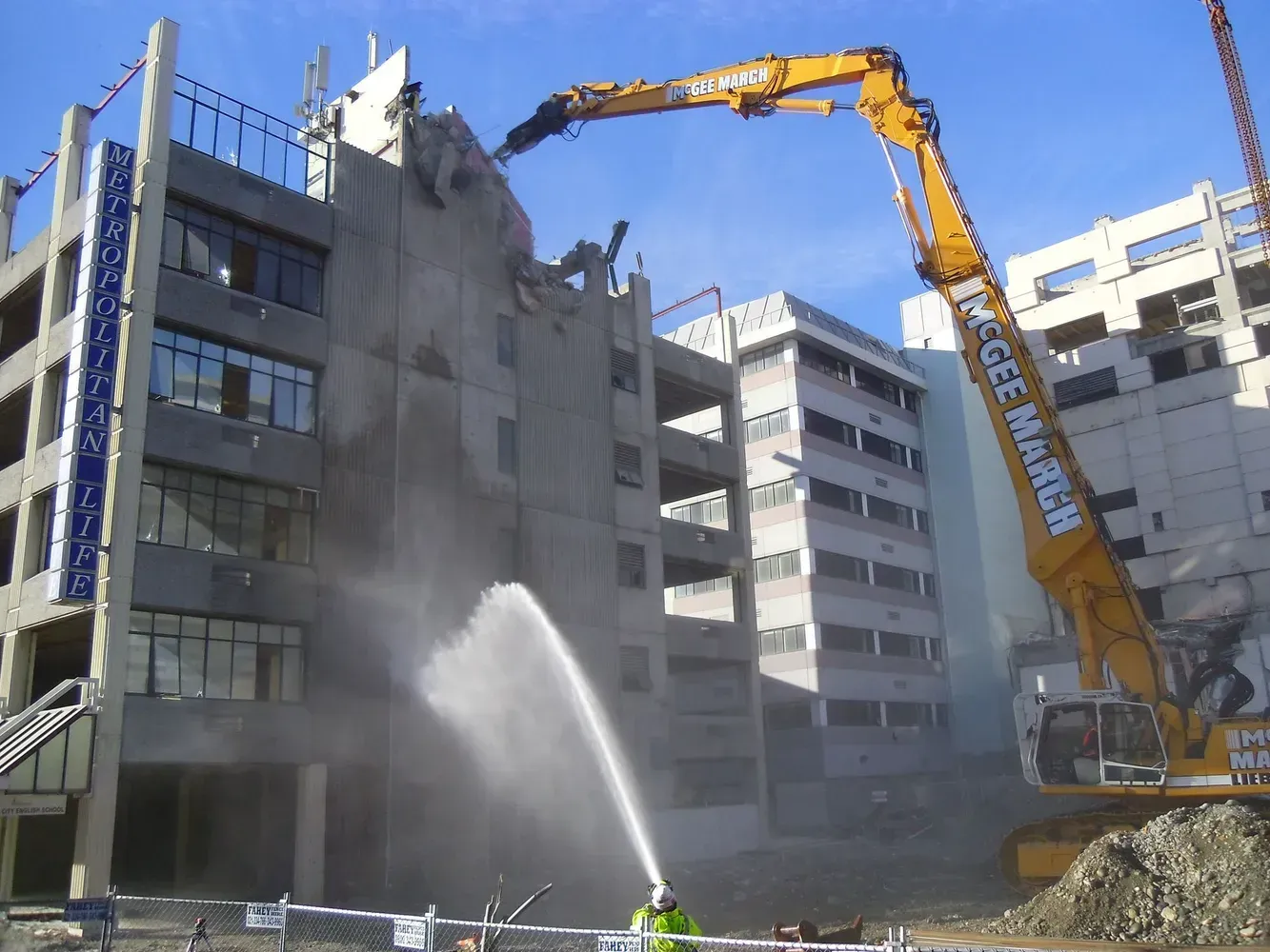 A large yellow excavator is demolishing a building