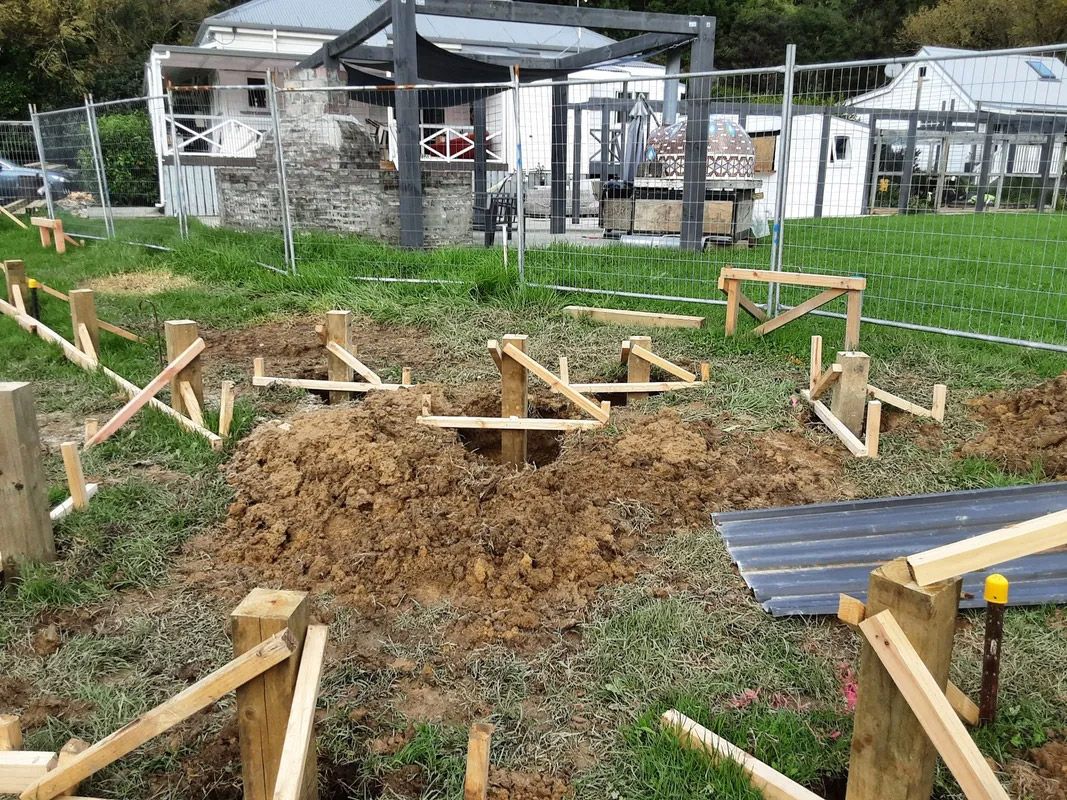 A wooden structure is being built in the dirt in front of a house.