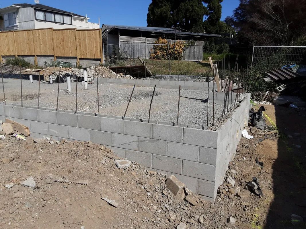 A concrete wall is being built in front of a house.
