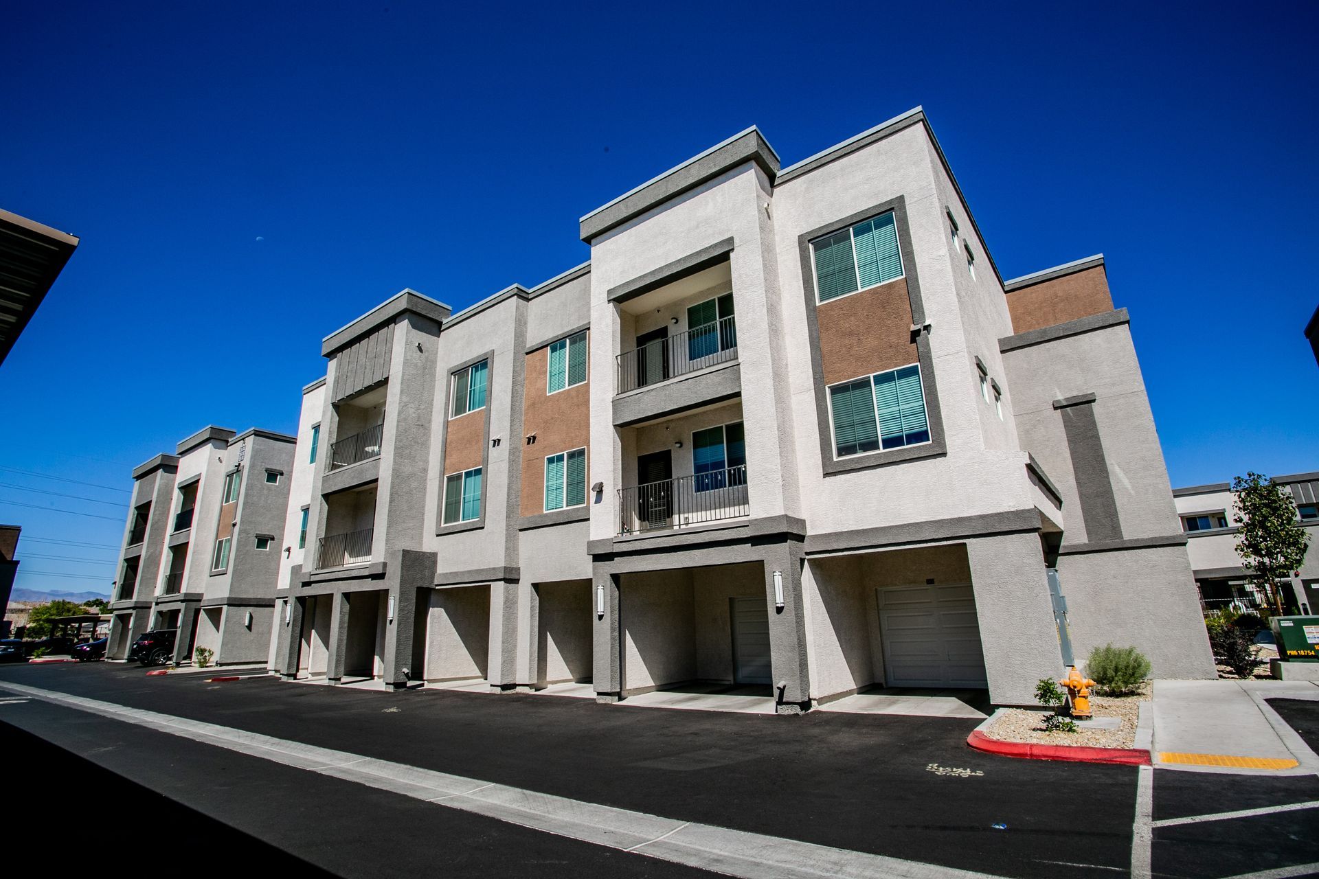 A large apartment building with a lot of windows and a fire hydrant in front of it.