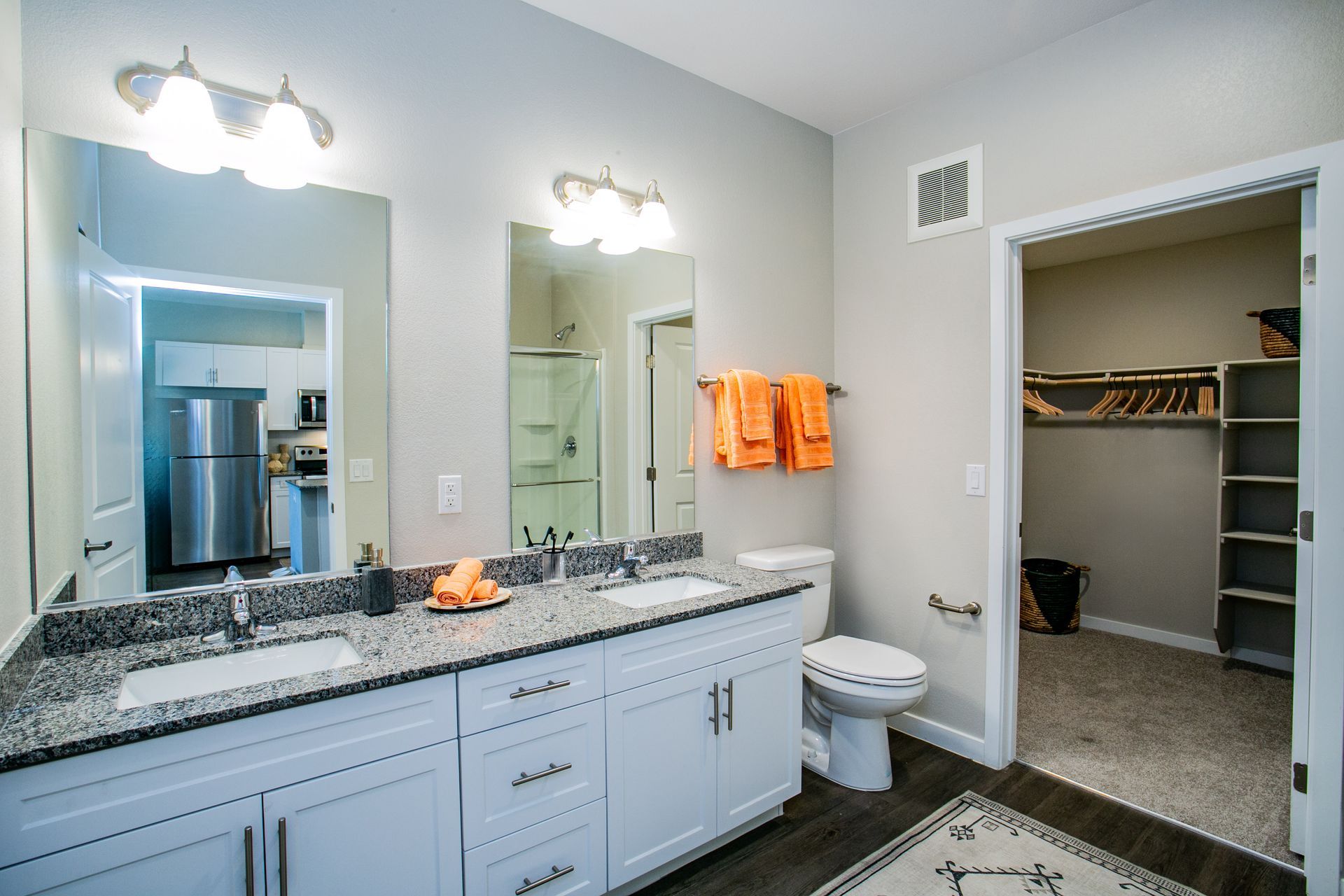 A bathroom with two sinks , a toilet , and a walk in closet.