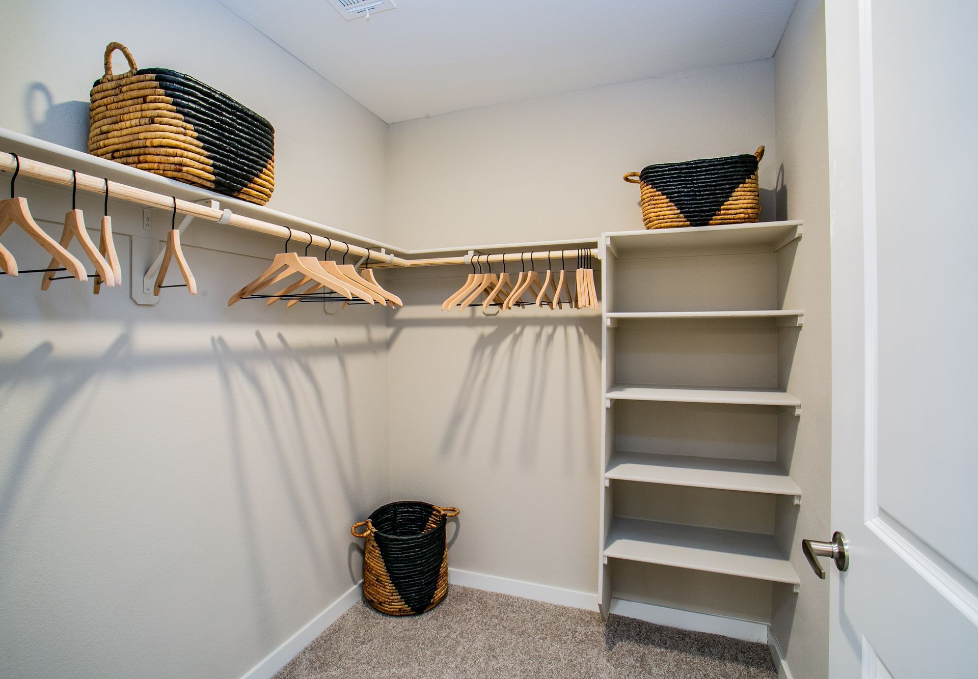 A walk in closet with clothes hanging on racks and shelves.
