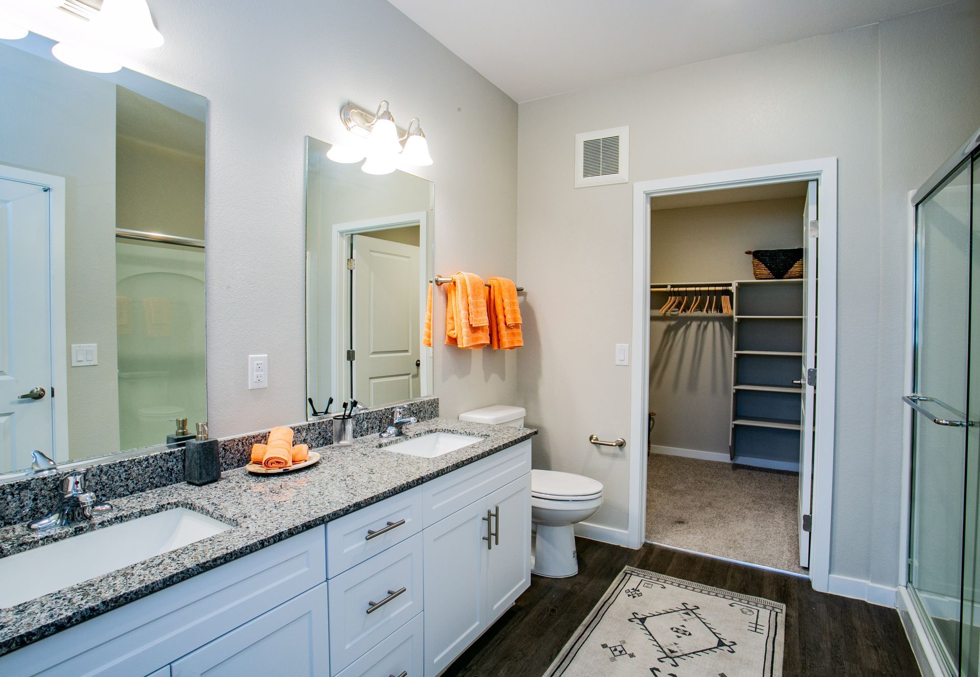 A bathroom with two sinks , a toilet , and a walk in closet.