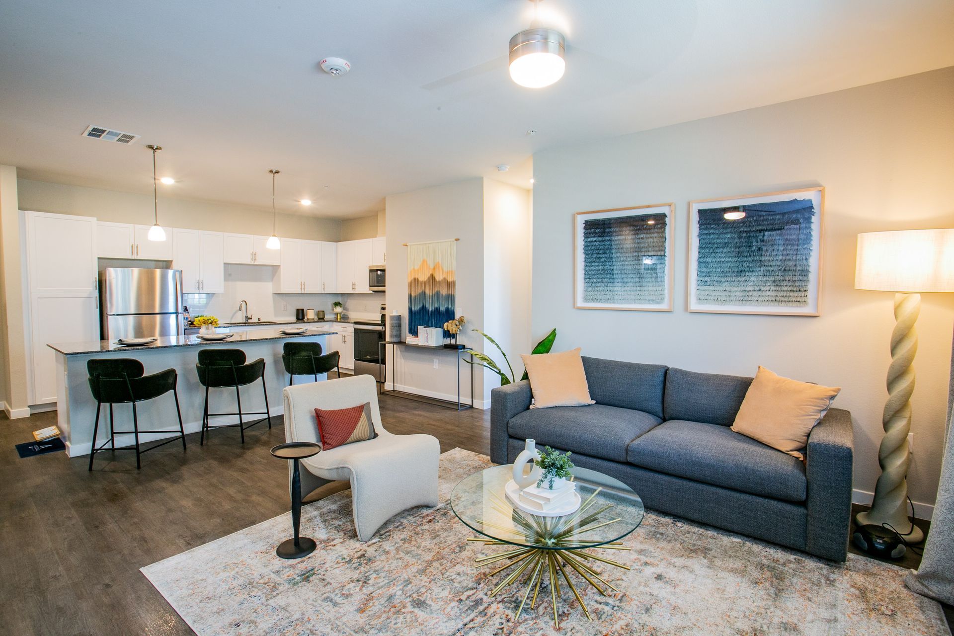 A living room with a couch , chair , coffee table and kitchen.