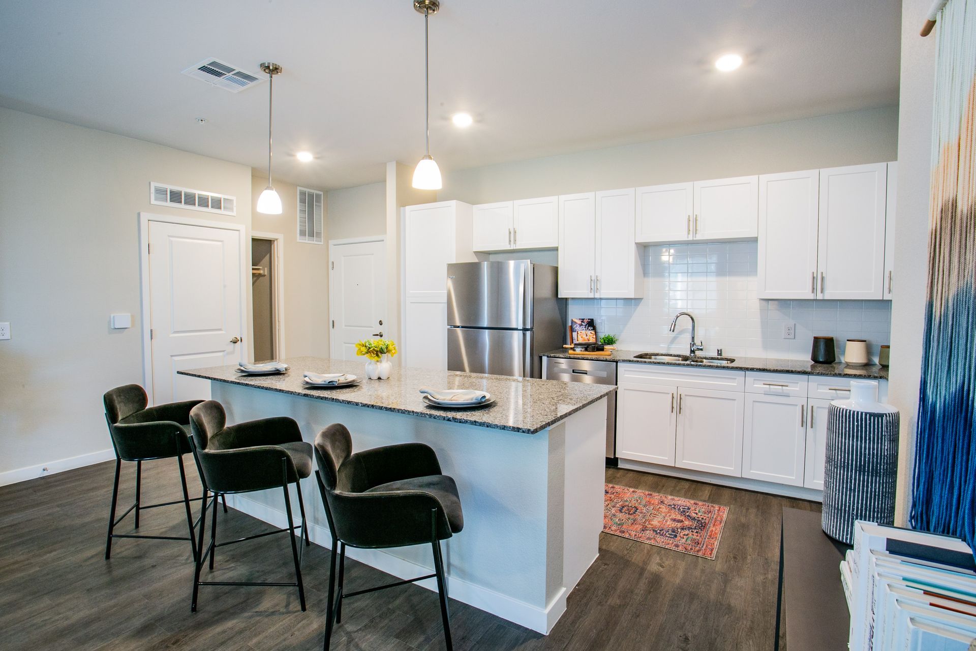 A kitchen with white cabinets , stainless steel appliances , and a large island.