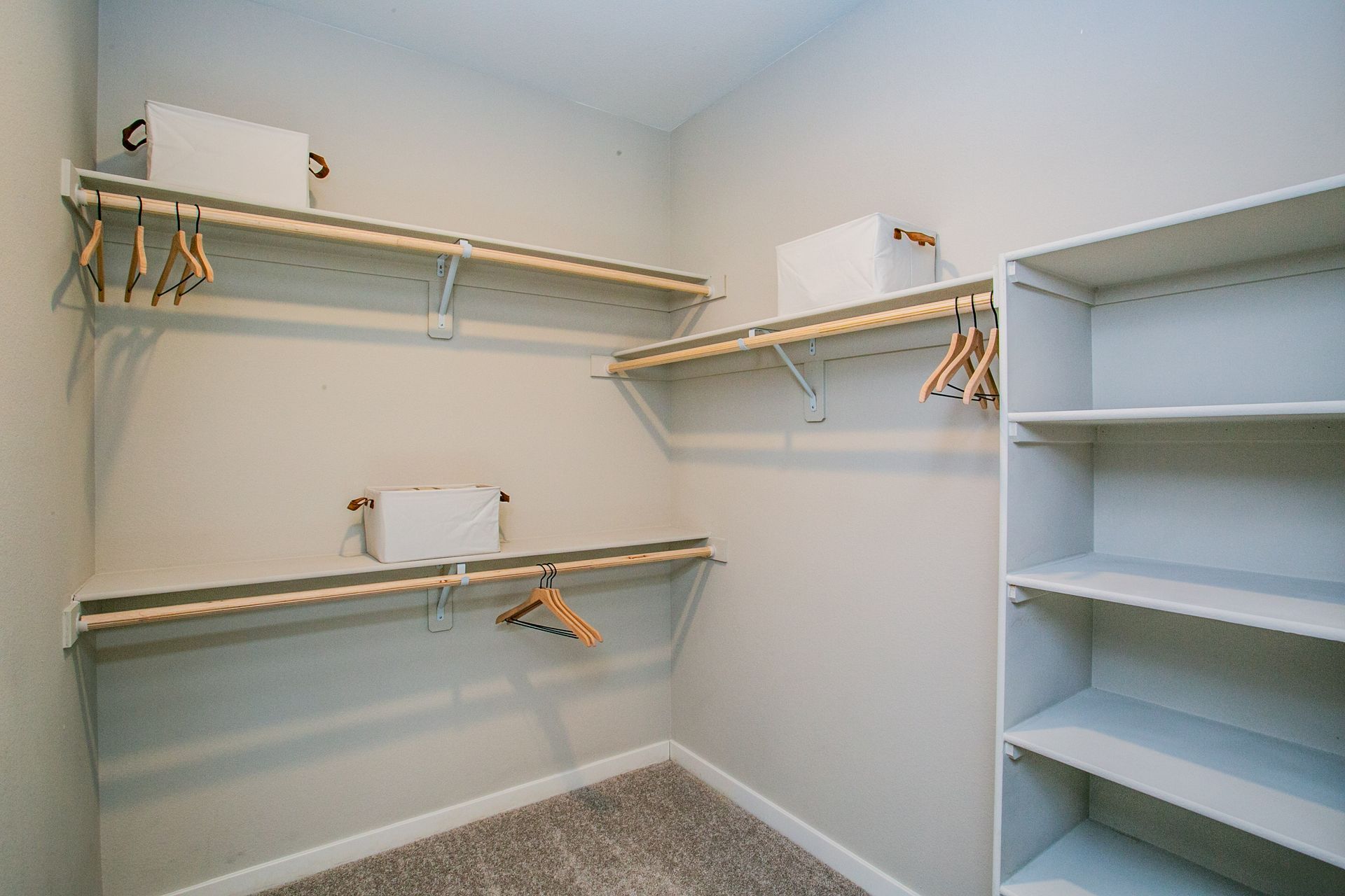 A walk in closet with a lot of shelves and clothes hanging on them.