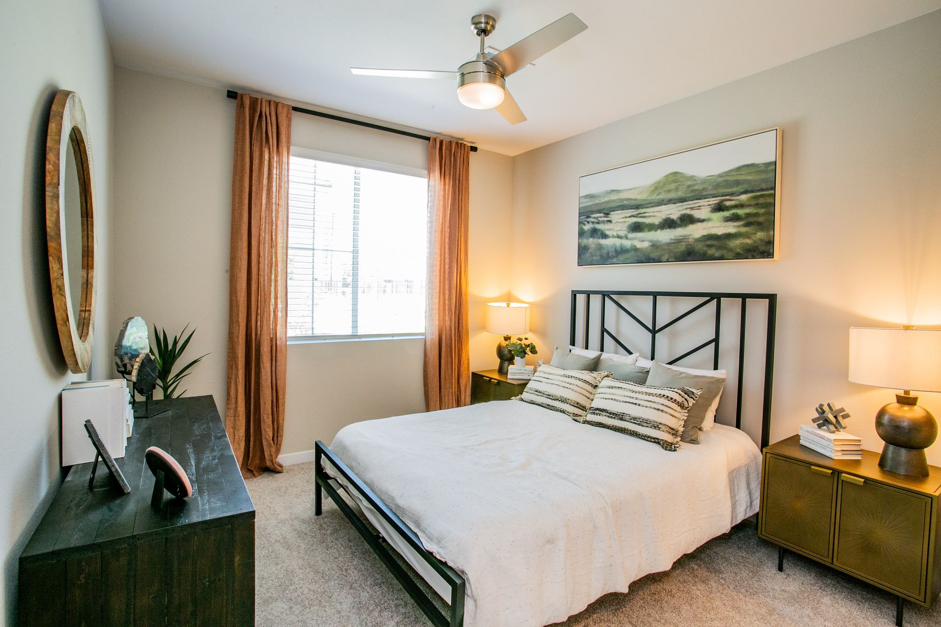A bedroom with a bed , dresser , nightstand , mirror and ceiling fan.