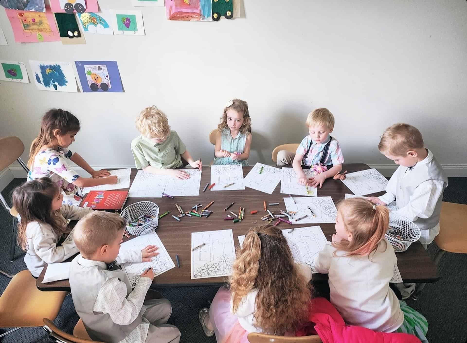 A group of children are sitting around a table drawing.