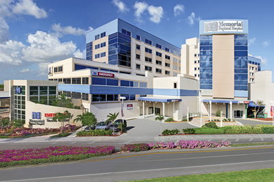 Memorial Regional Hospital building with blue and white accents, sunny sky.