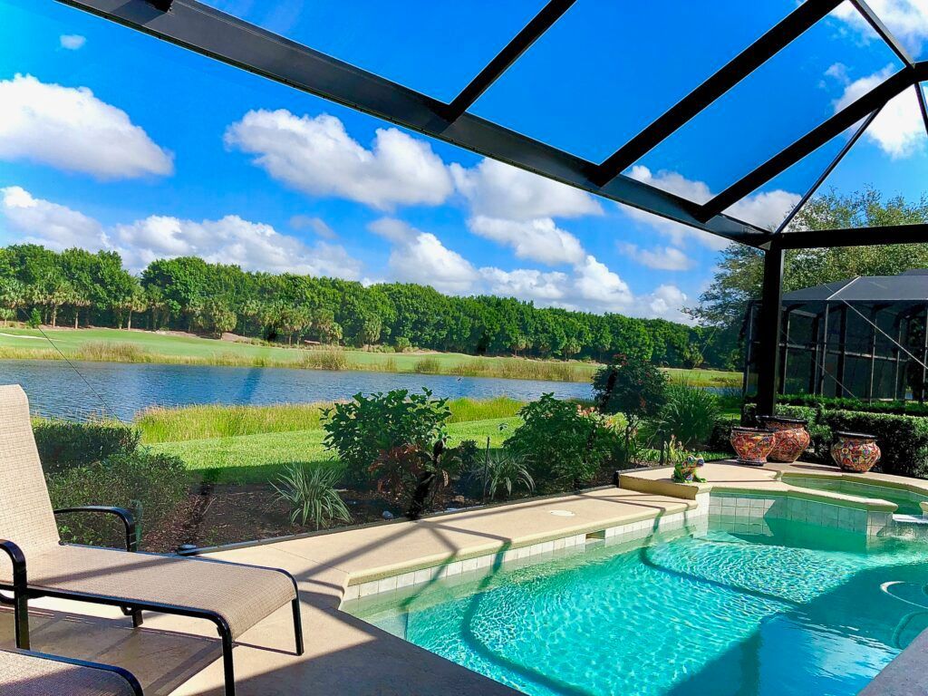 Screened-in porch with white trim, dark walls, and a decorative door. Green grass and plants are in the foreground.