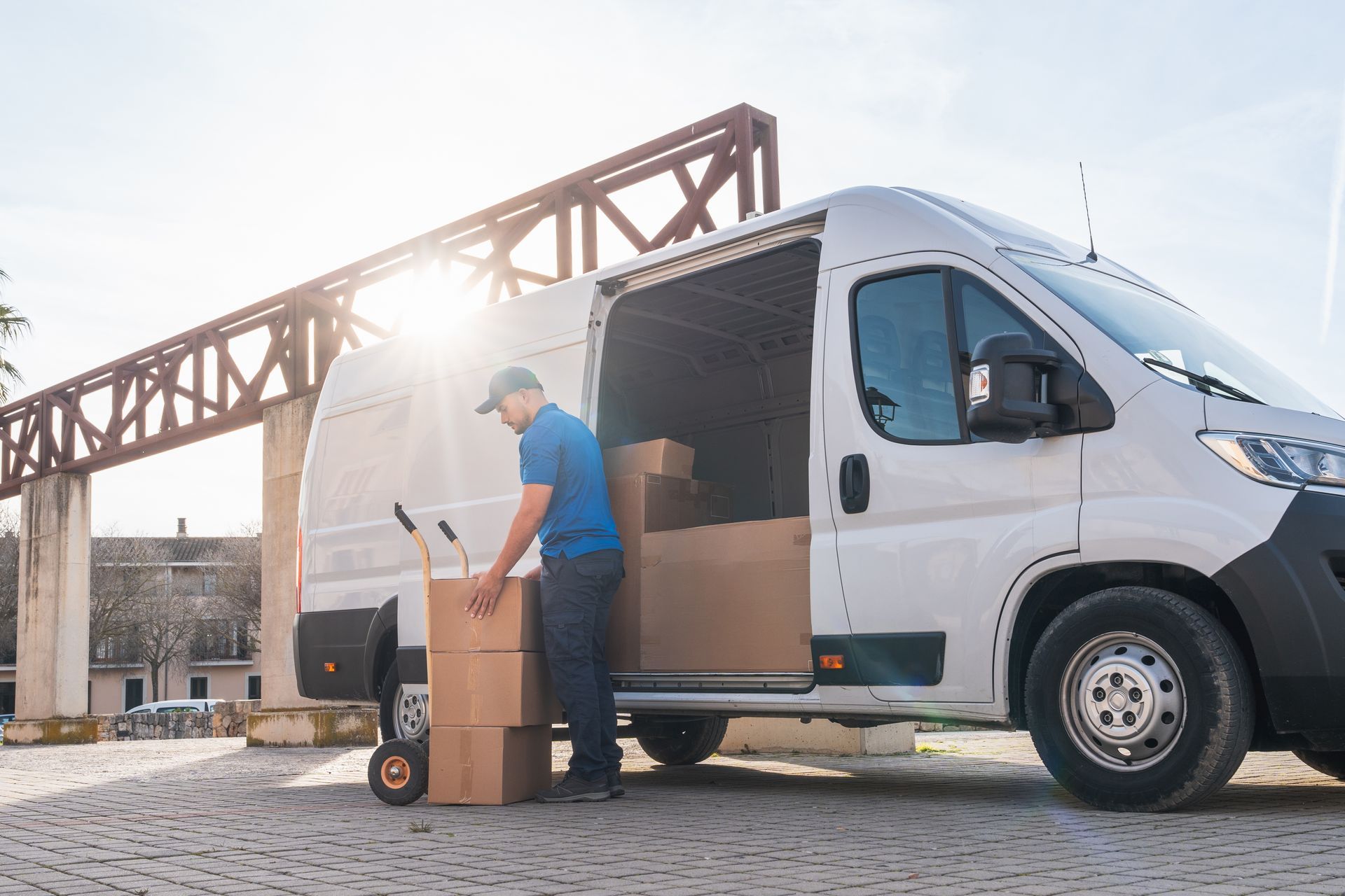 Delivery person loading cardboard boxes into a white van