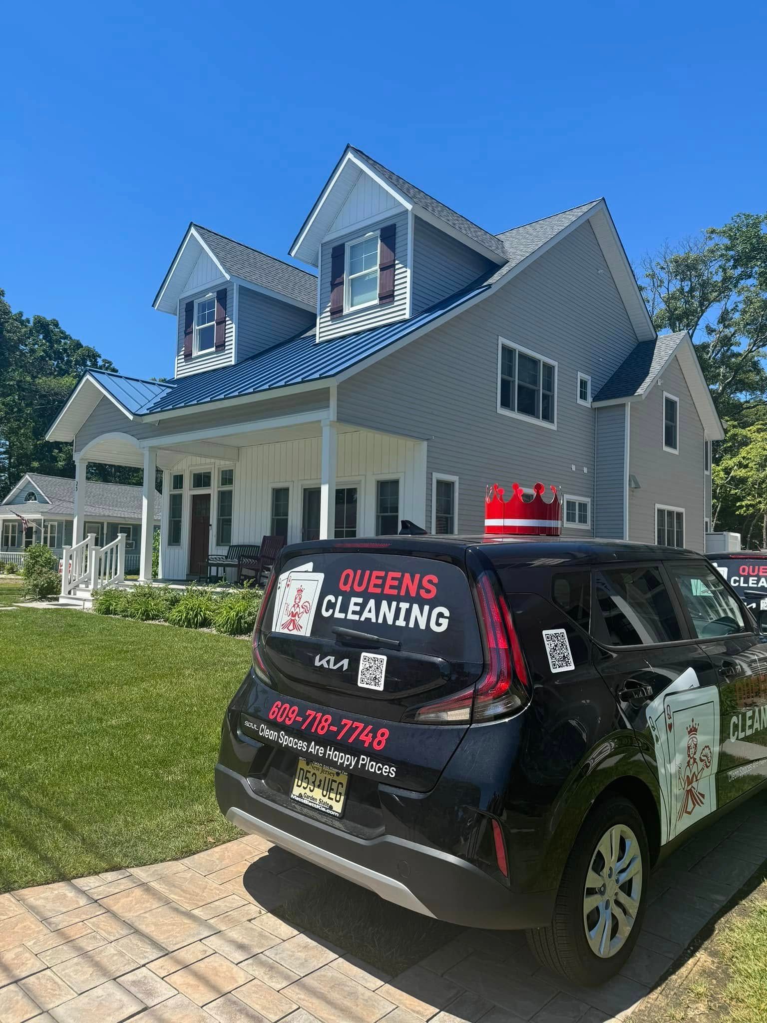 A black car is parked in front of a large house.