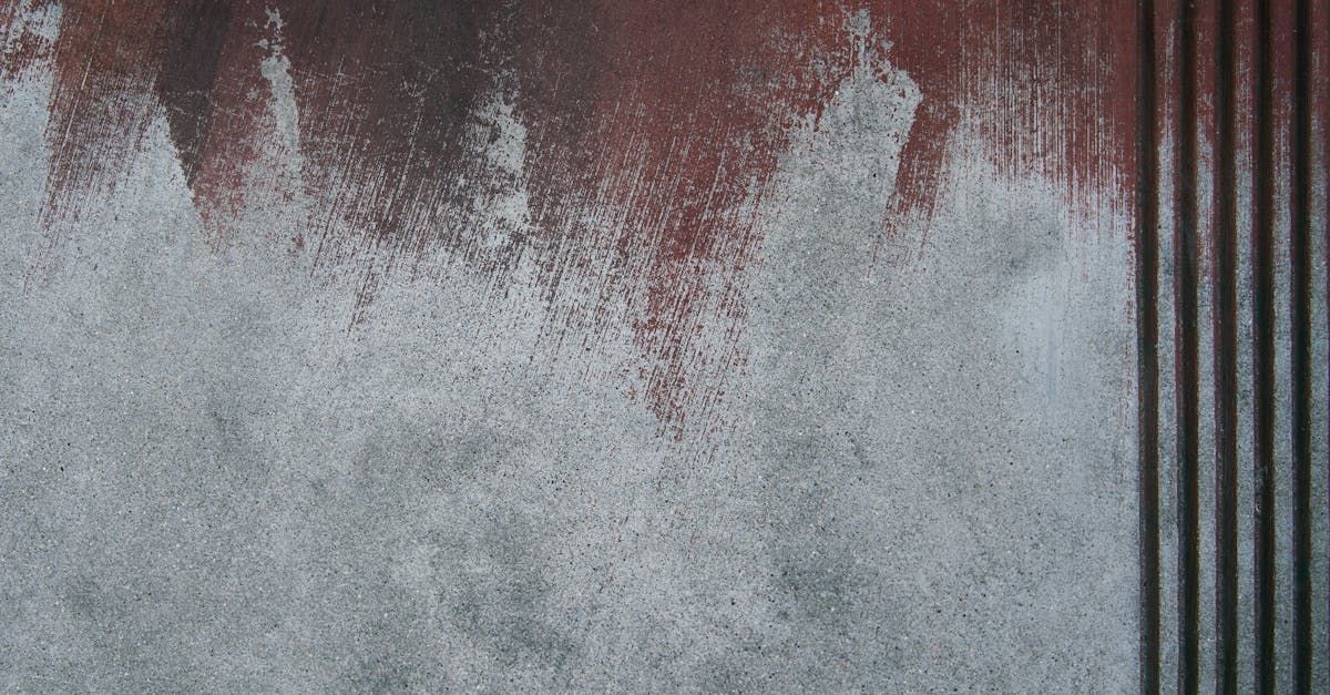 Construction workers in industrial hall applying grey epoxy resin to the floor to create a smooth and durable surface.