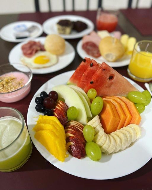 Um prato de frutas está sobre uma mesa com outros pratos de comida