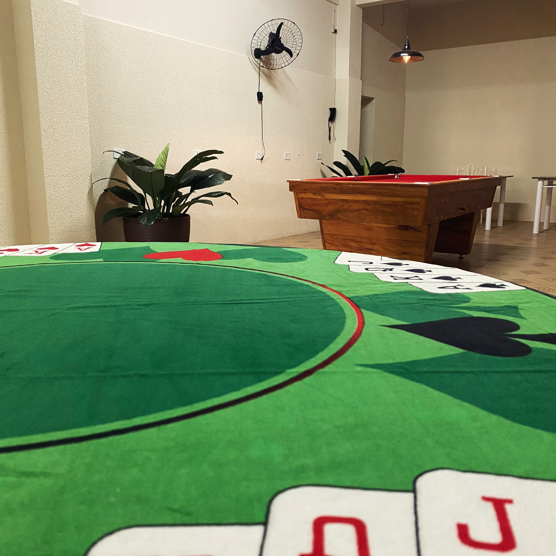 Uma mesa de sinuca em uma sala com cartas de baralho no chão