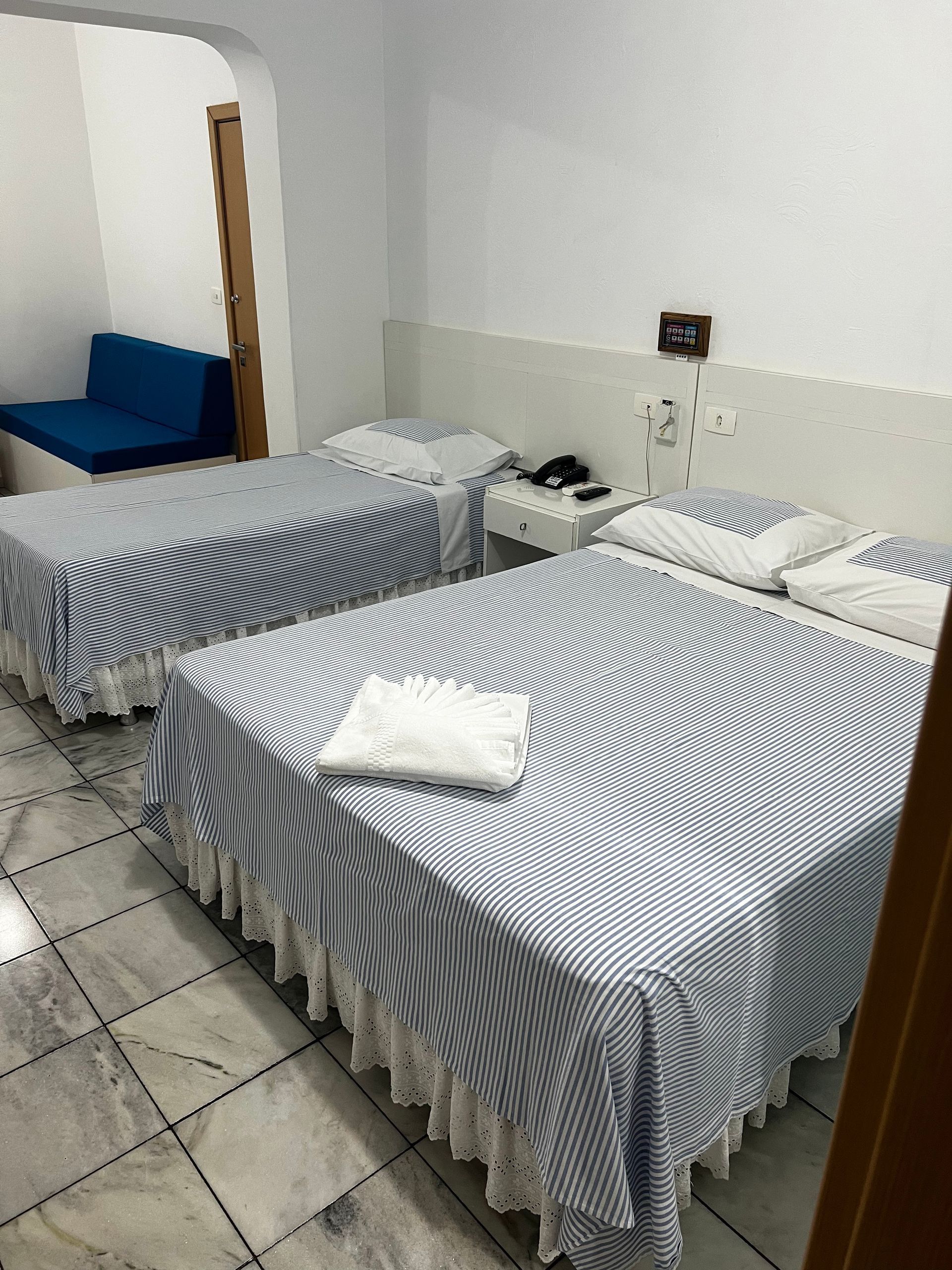 Um quarto de hotel com duas camas e uma cadeira azul.