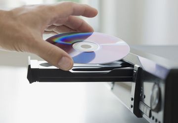 A person is putting a cd into a cd player.