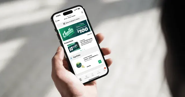 Hand holding a smartphone displaying a green shopping or rewards app interface