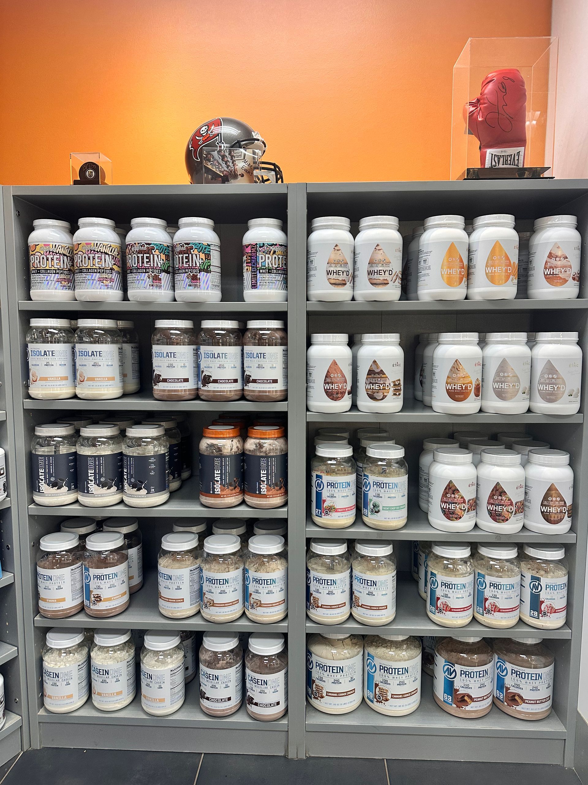 Shelves stocked with various jars and containers, against an orange wall.
