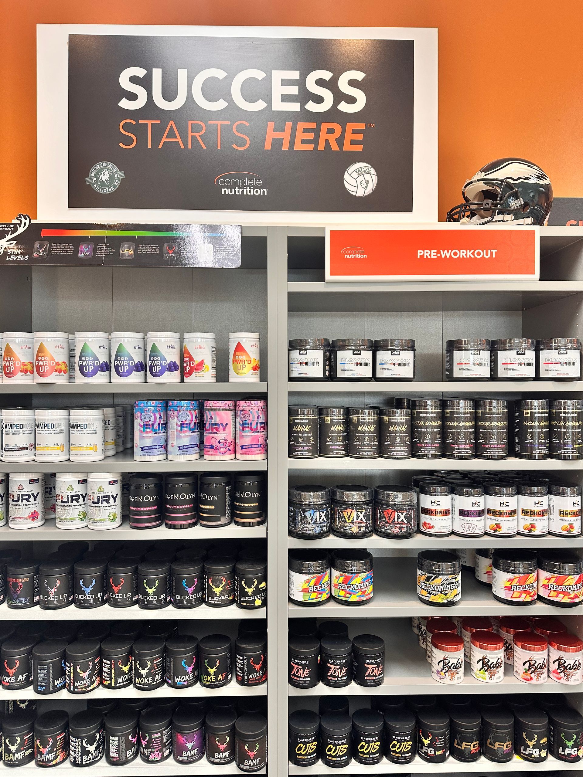 Shelves stocked with various sports nutrition supplements in a brightly lit store with the sign 