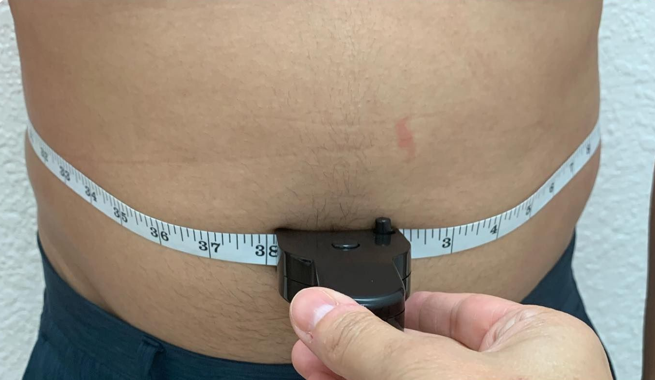 Hand measuring abdomen with a tape measure around the waist