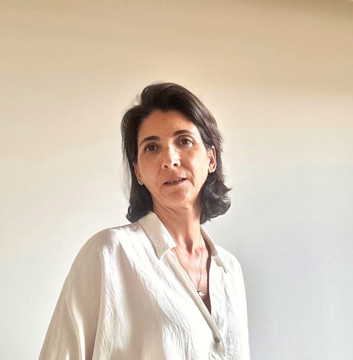 Un primer plano del rostro de una mujer que lleva una camisa blanca y pendientes.