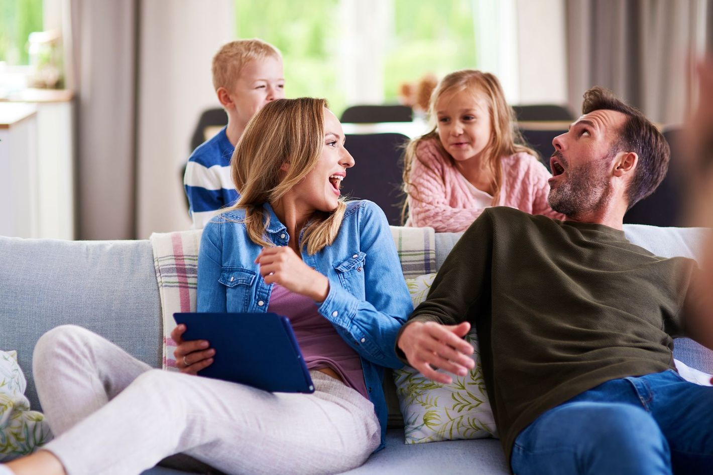 Una familia está sentada en un sofá viendo la televisión.
