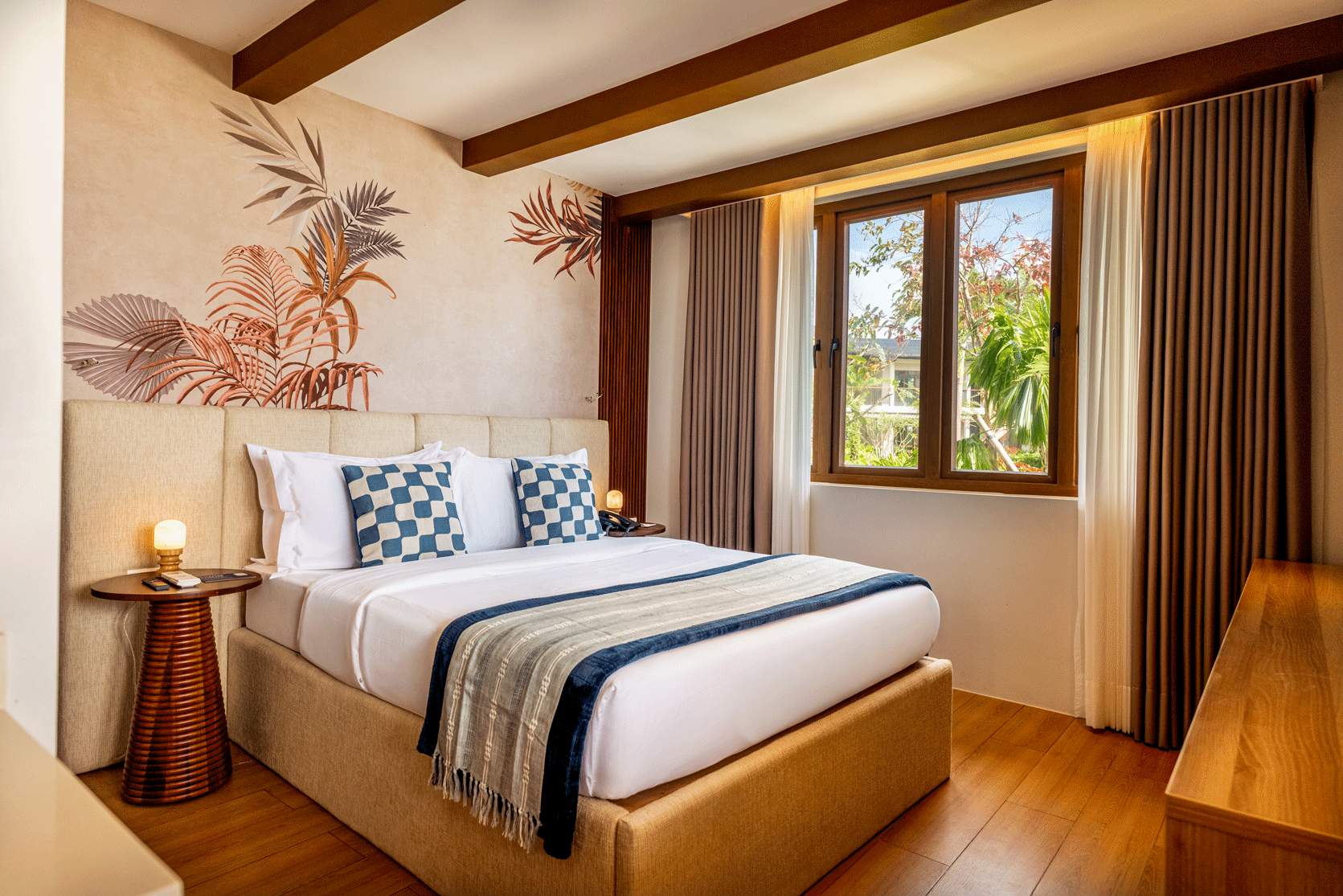 Bright bedroom with a neatly made bed, floral wall art, and a window with curtains.
