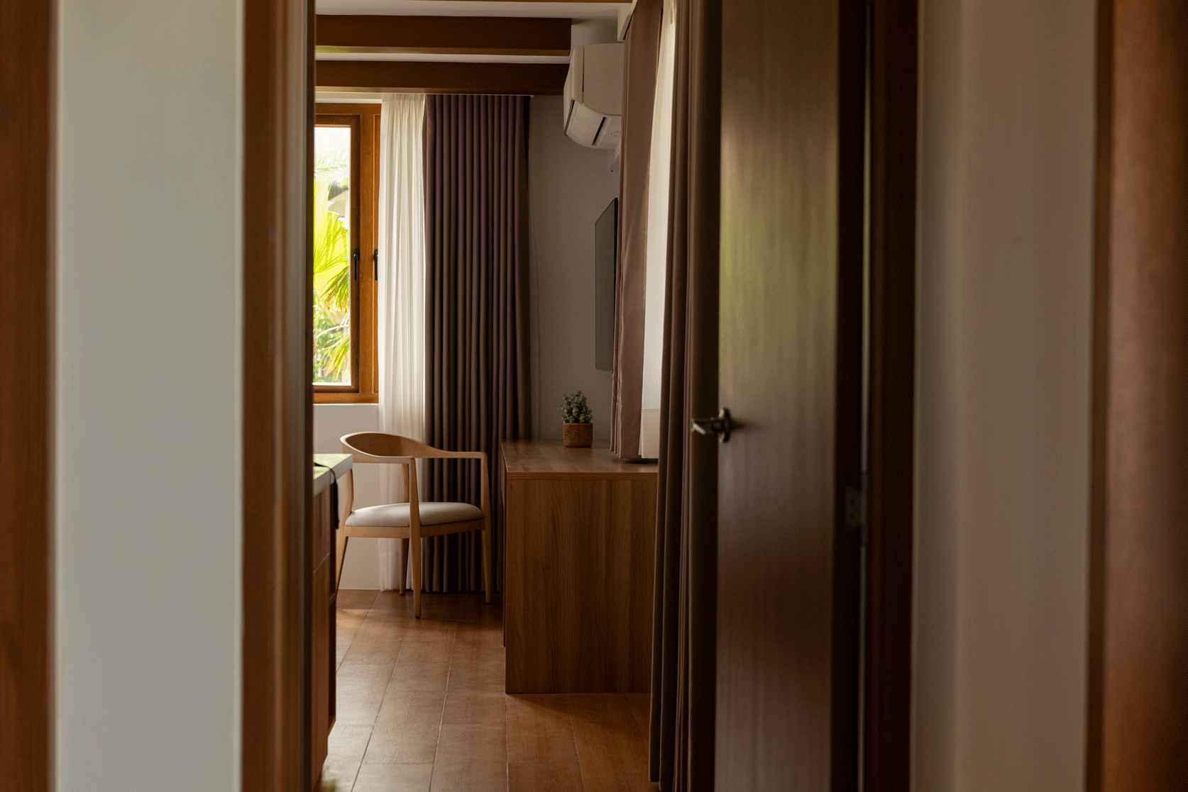 Cozy hotel room with wooden desk, chair, and tropical view at Harvest Hotel