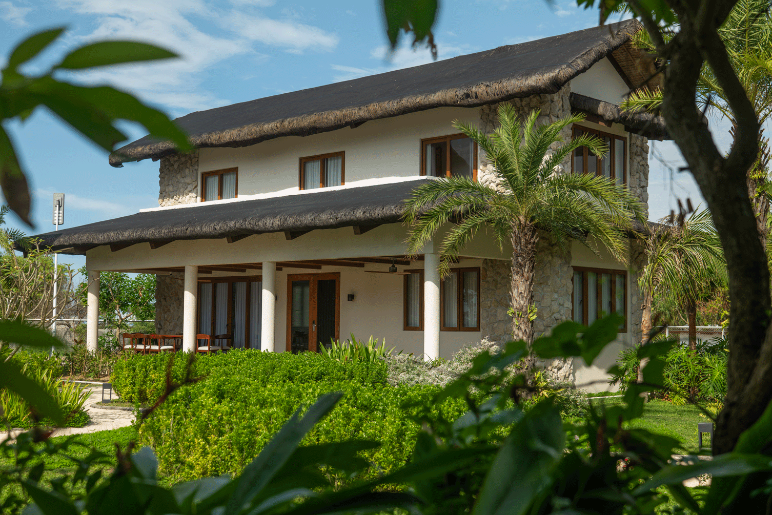 Harvest Hotel Cabanatuan tropical villa with thatched roof and lush garden