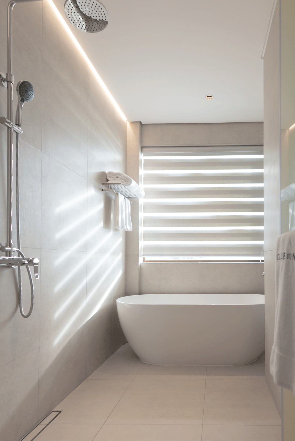Luxurious hotel bathroom with freestanding tub and rain shower at Harvest H