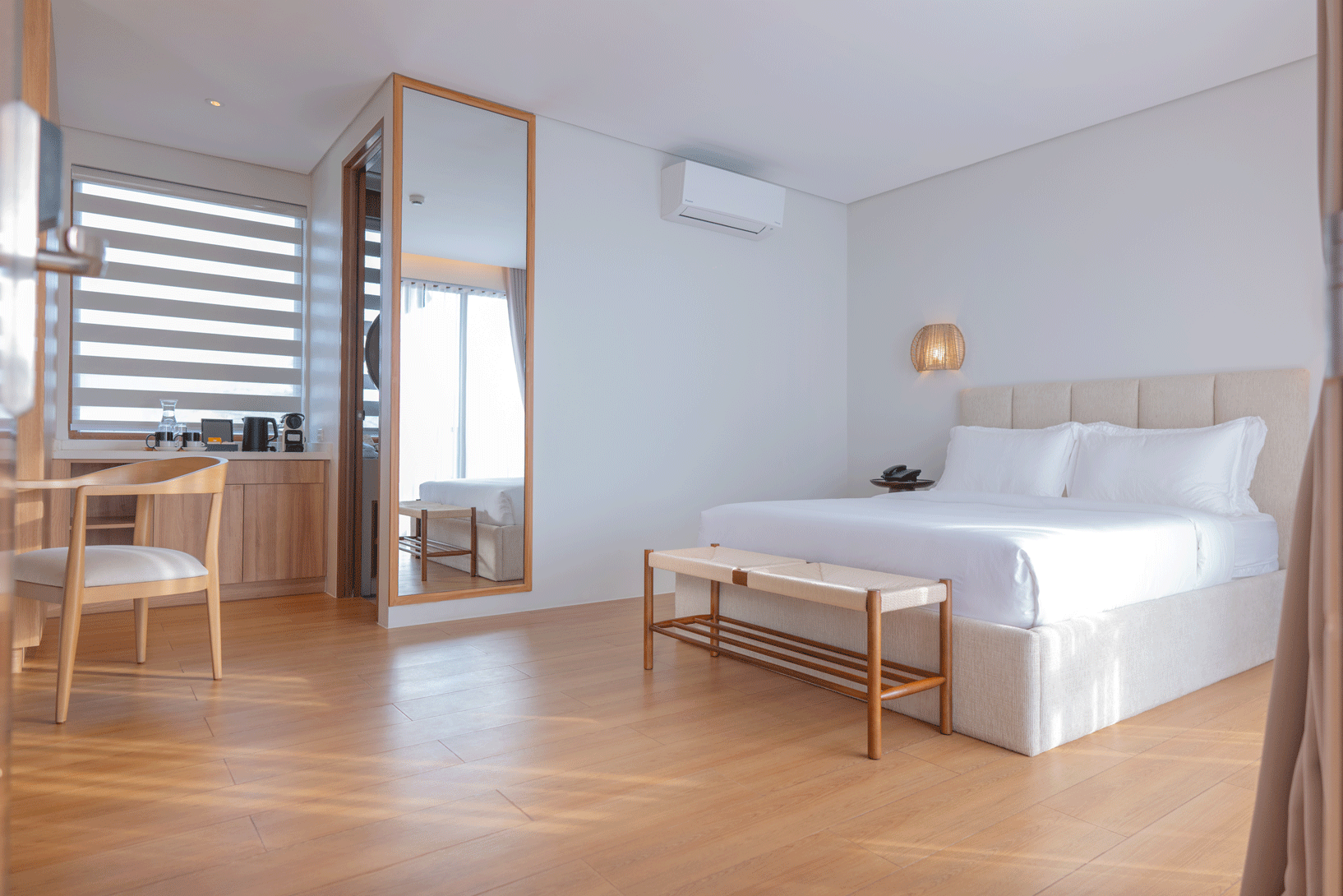 Bright minimalist hotel room with king bed and wood floors at Harvest Hotel