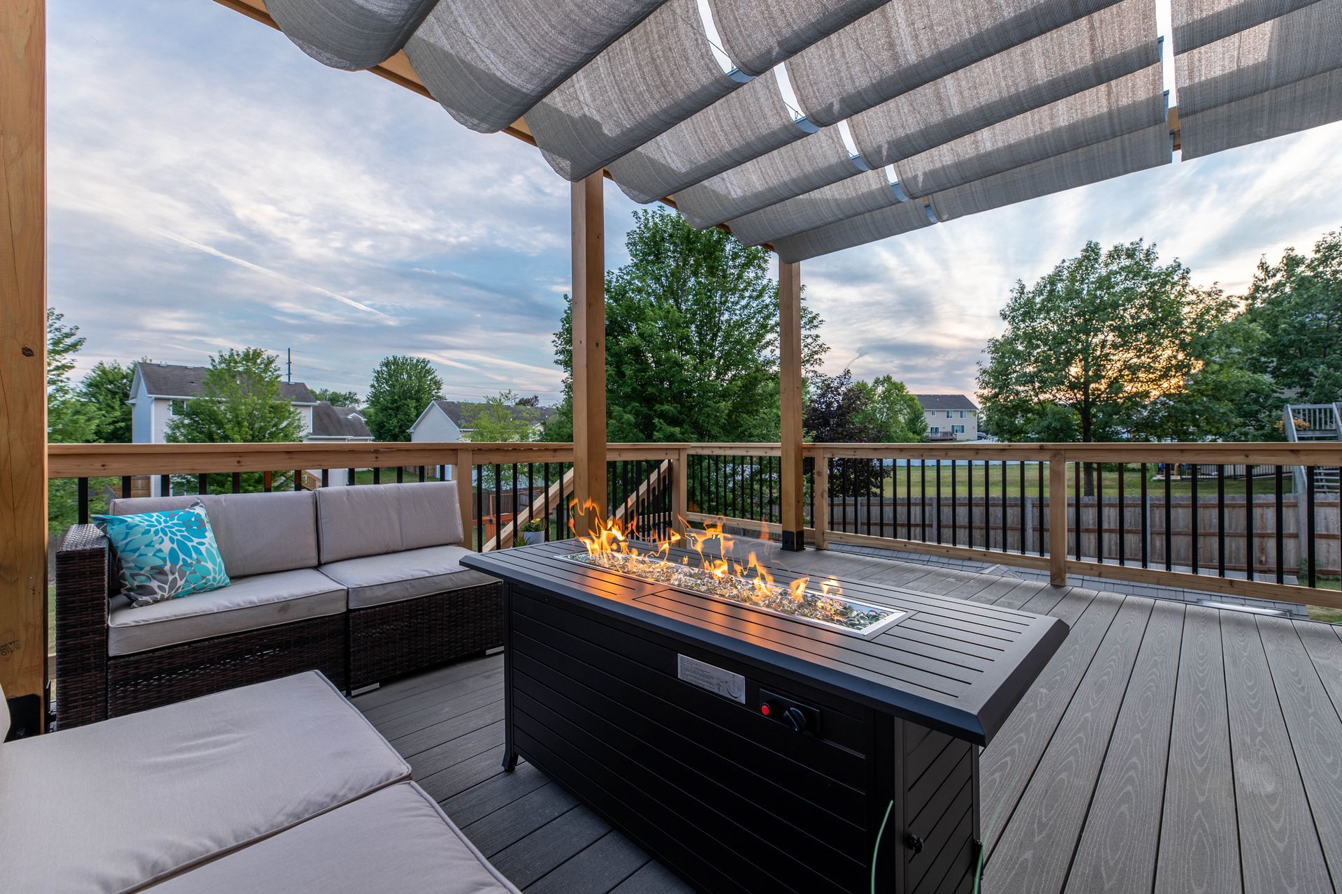 A patio with a fire pit and a couch under a pergola.