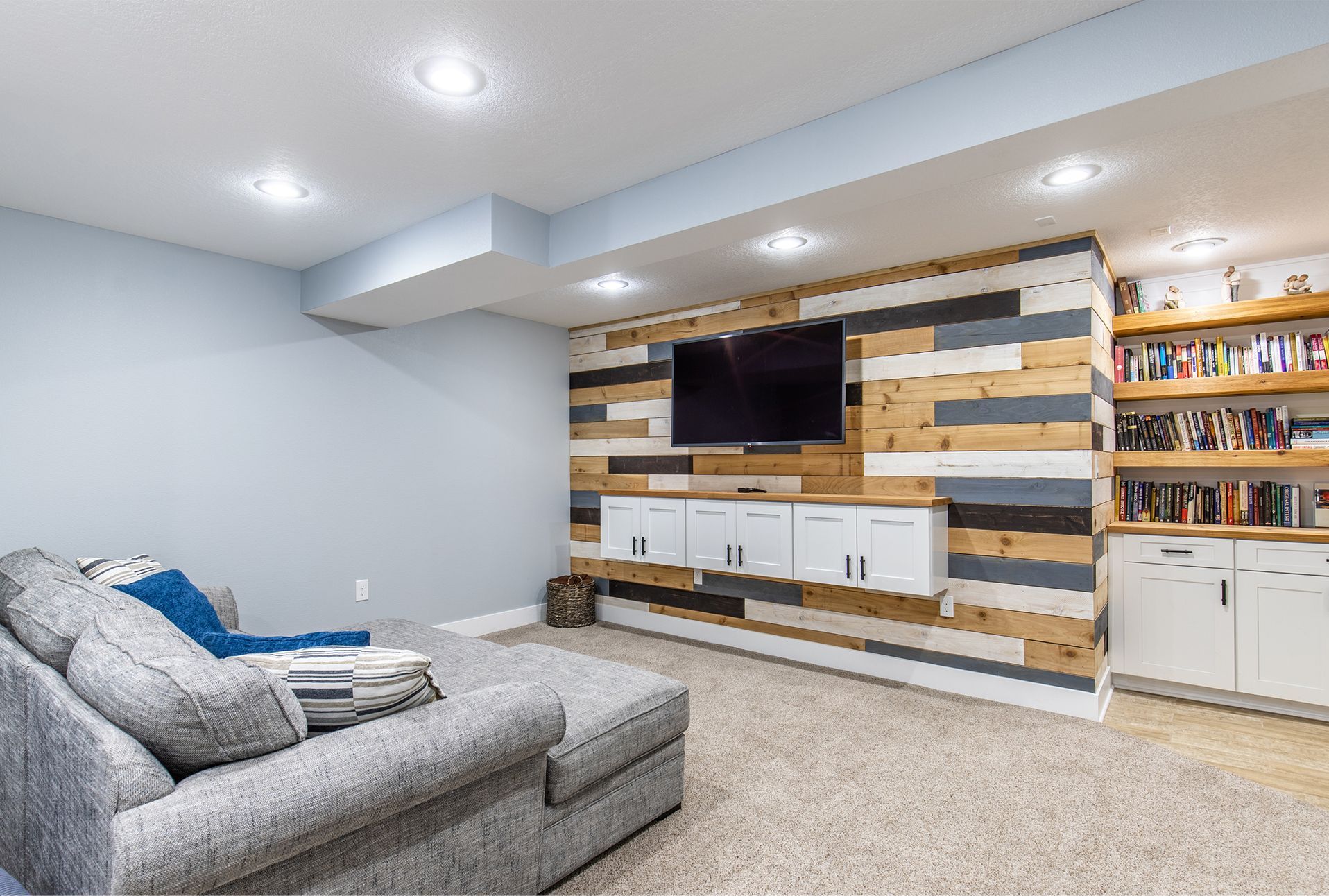 A living room in a basement with a wooden wall and a flat screen tv.