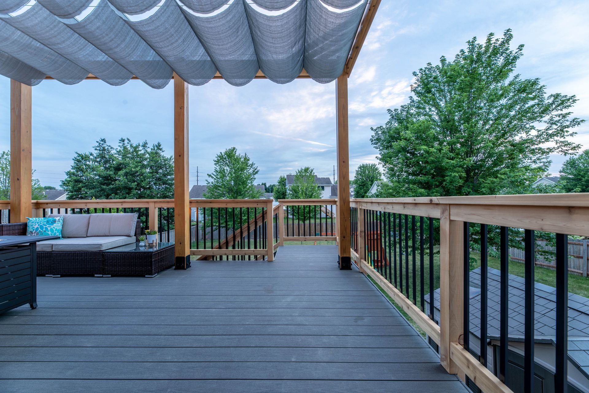 There is a couch on the deck with a canopy over it.