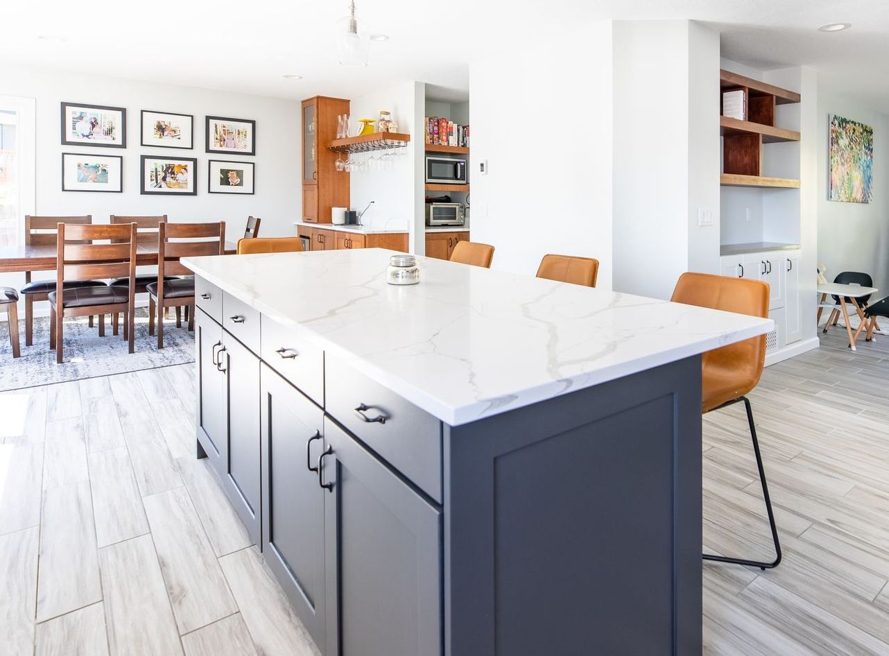 A kitchen with a large island in the middle and a dining room in the background.