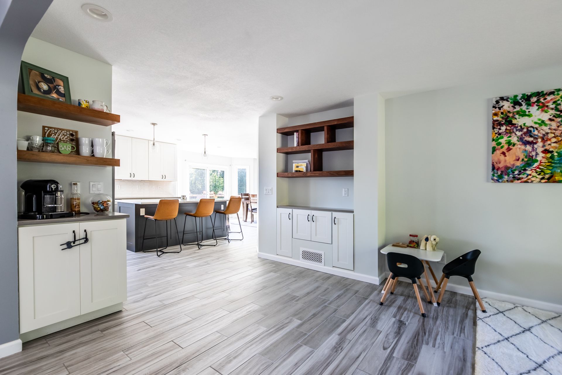 A living room with a table and chairs and a kitchen in the background.