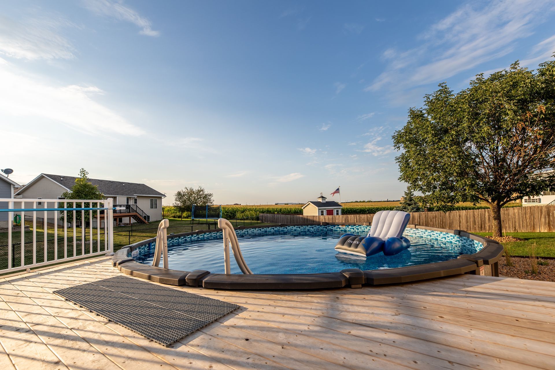 A large swimming pool is sitting on top of a wooden deck.