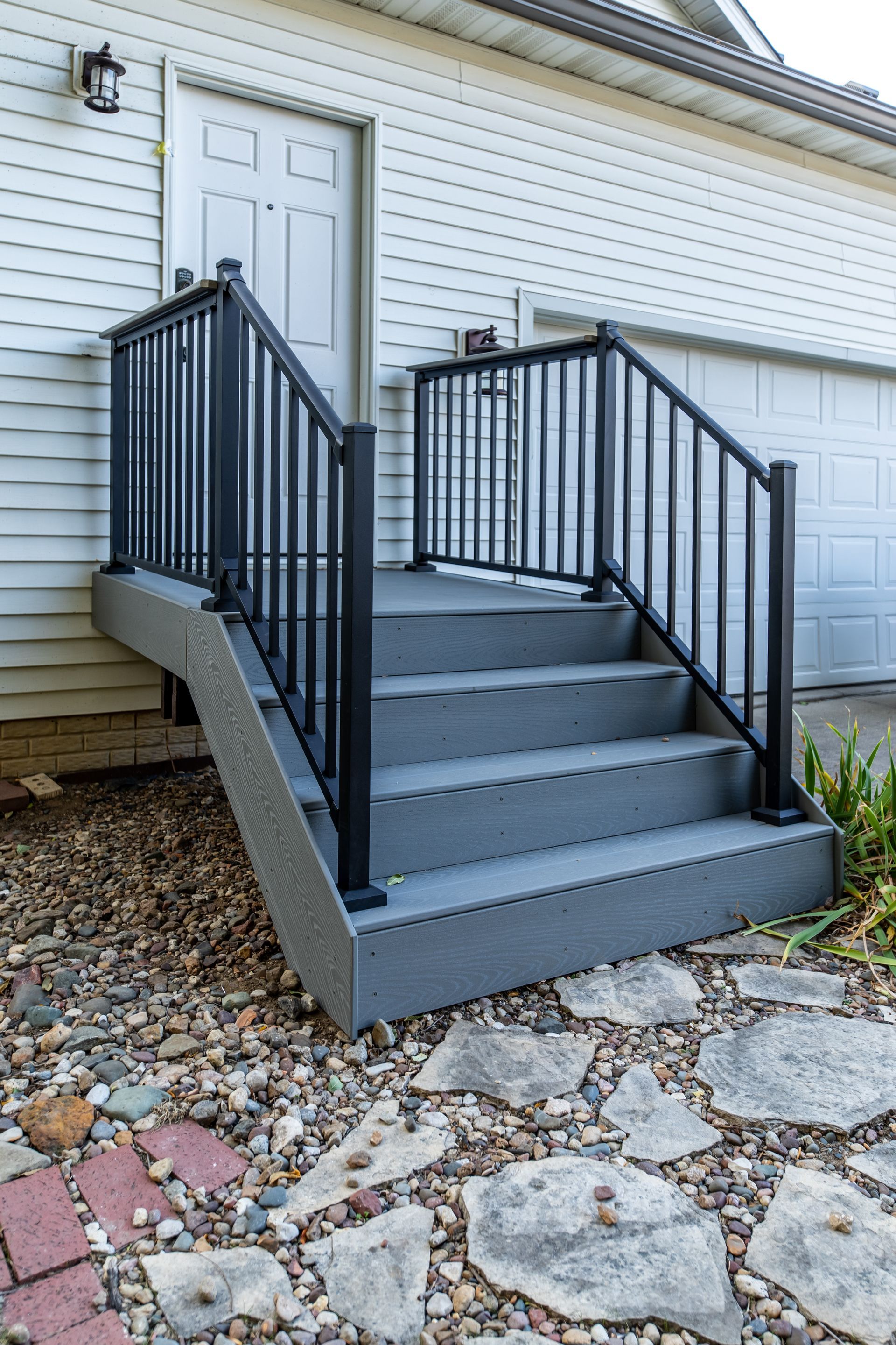 A set of stairs leading up to a house with a black railing.