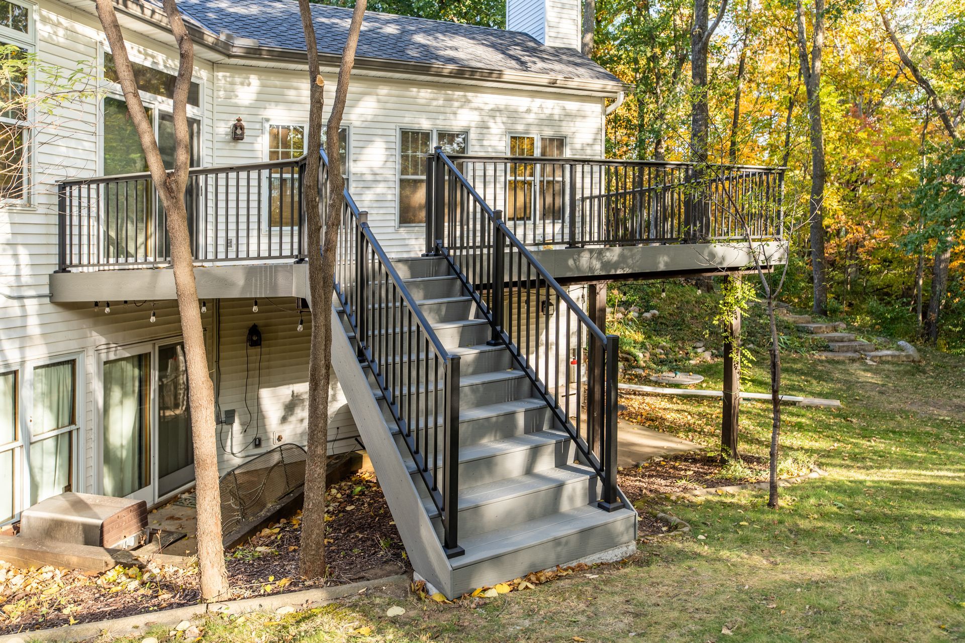 A white house with a deck and stairs leading up to it.