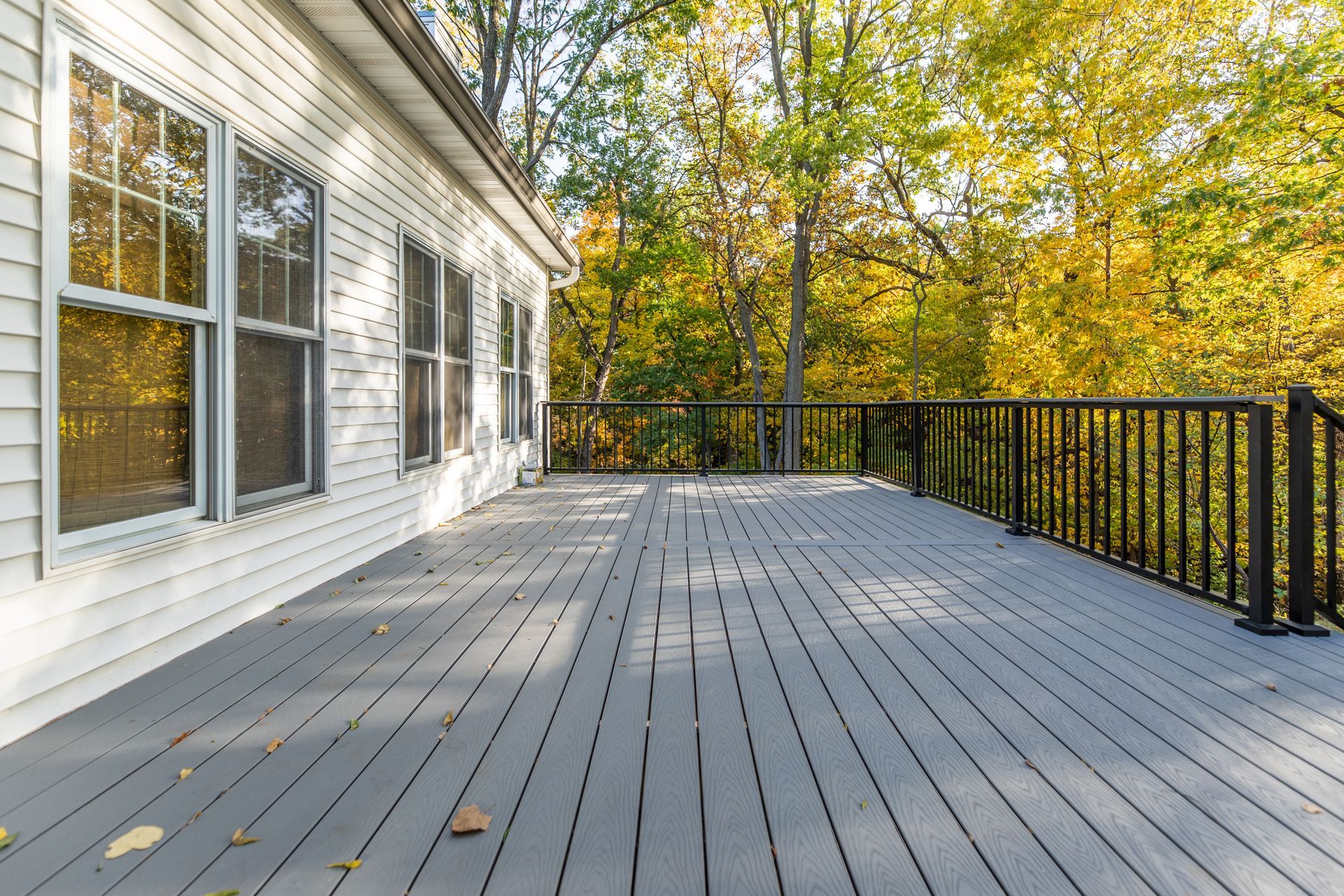 An empty deck with a railing and trees in the background.