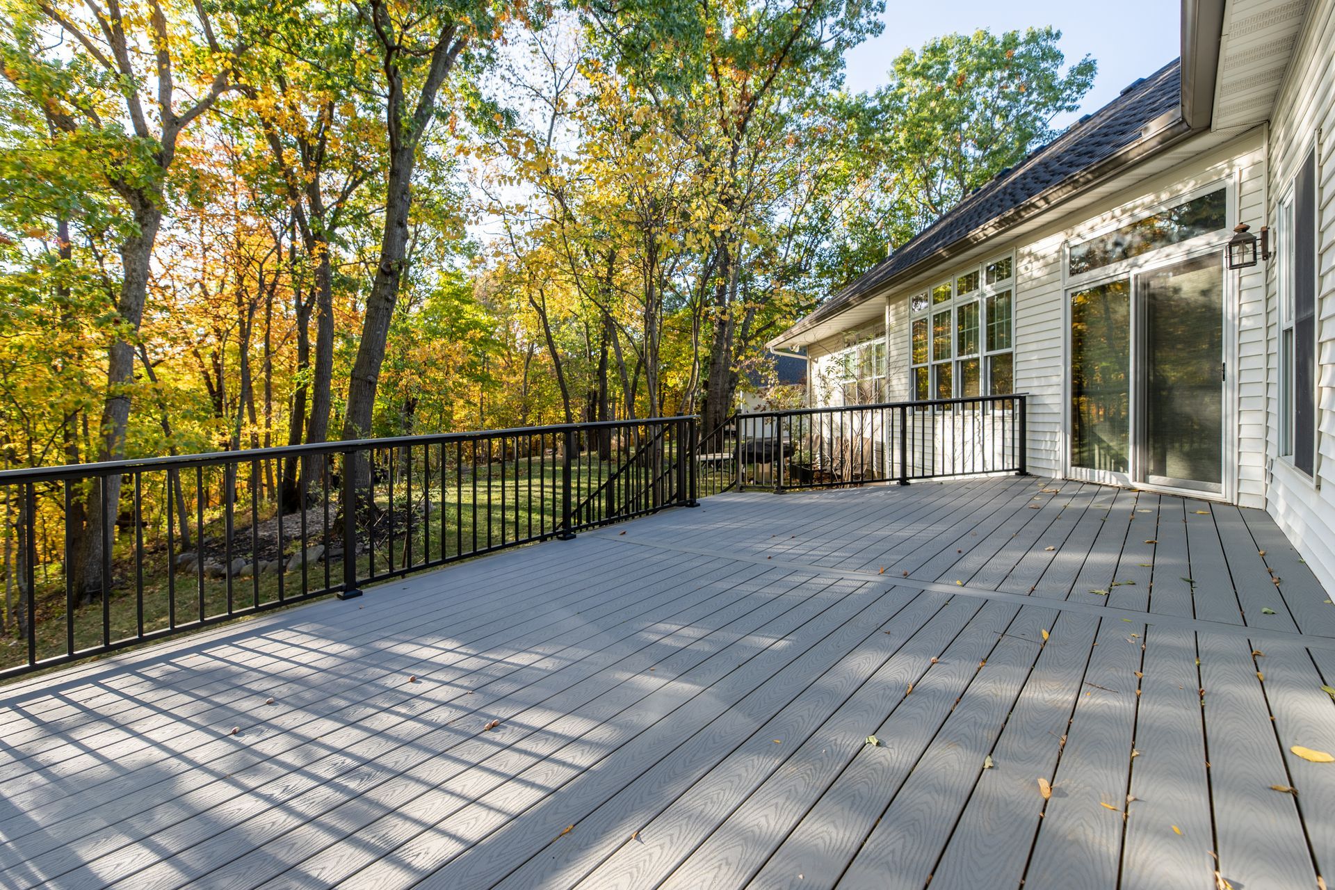 There is a large deck with a railing and trees in the background.