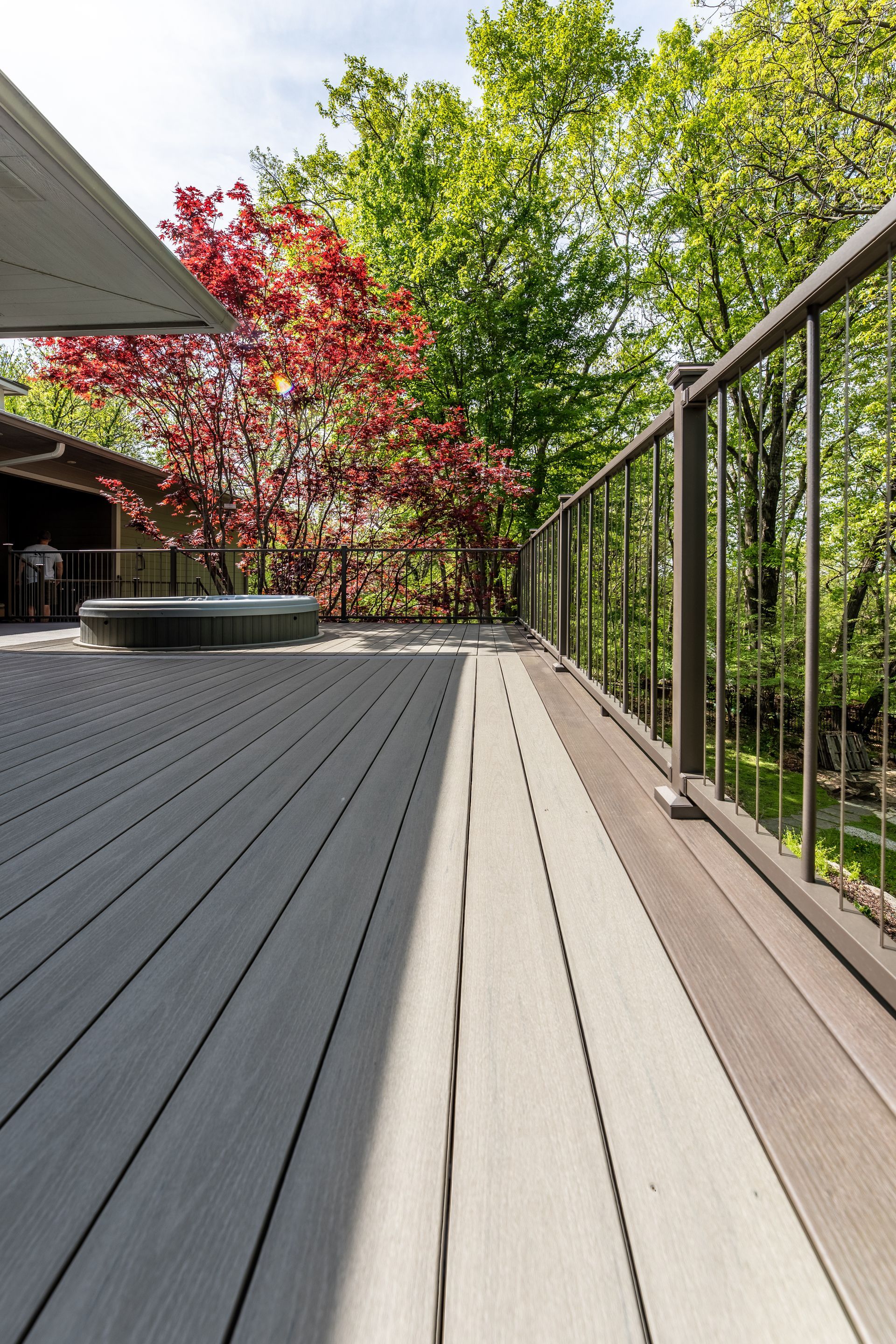 A wooden deck with a metal railing and trees in the background.